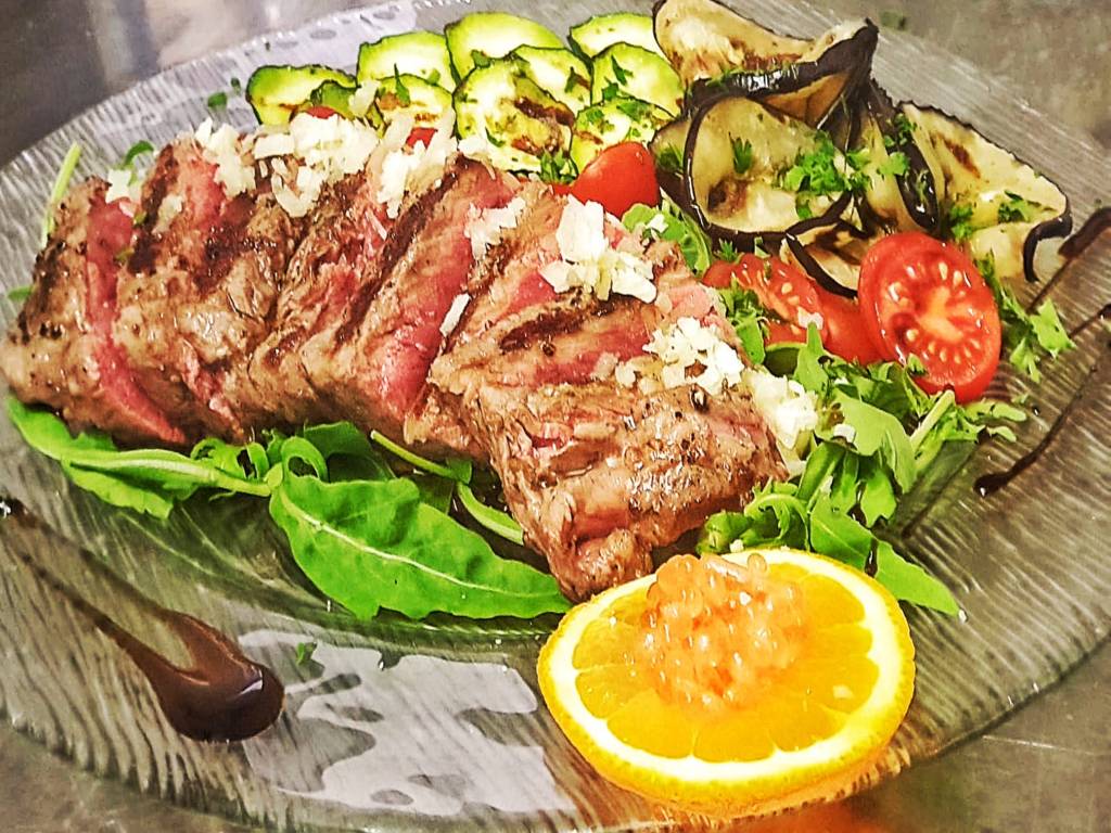 Geschnittenes Fleisch mit gegrilltem Gemüse.